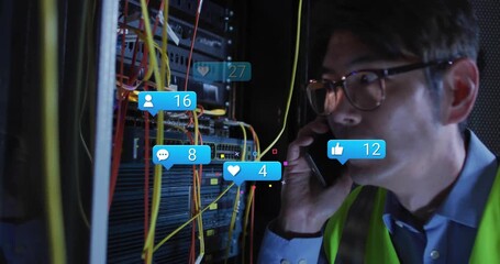 Male technician speaking into phone beside network rack with cables showing floating social icons - Powered by Adobe