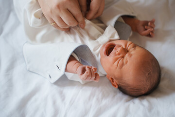 Baby crying during outfit change on white blanket