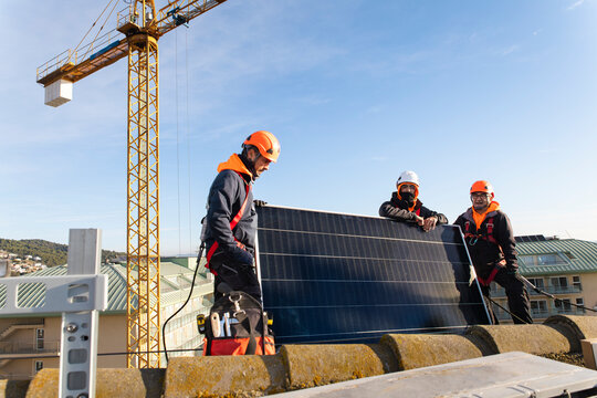 Construction workers installing solar panel on rooftop