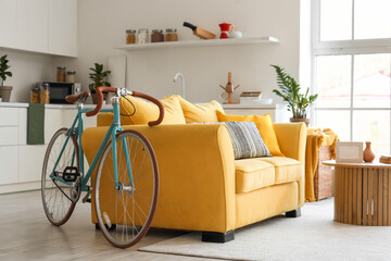 Interior of living room with yellow sofa, coffee table, counters and bicycle