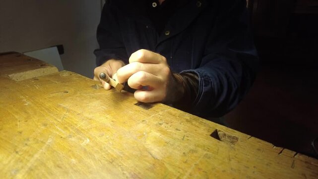Craftsman meticulously shaping a violin bow stick with precision tools
