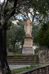 Obraz premium Statue of the Virgin Mary set among trees at Abbaye Saint-Michel de Frigolet, blending religious devotion with a tranquil natural setting in Provence.