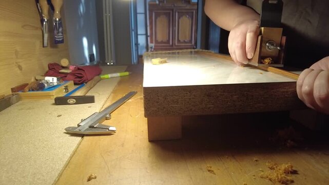 Craftsman meticulously shaping a wooden stick with a specialized tool for instrument making