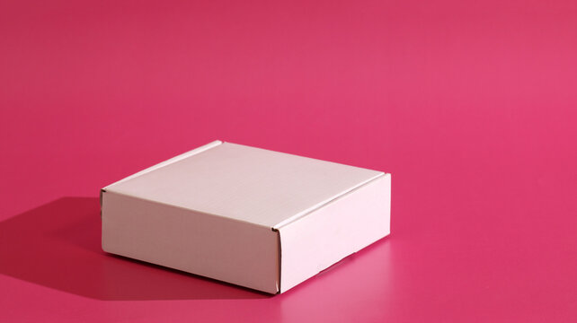 White shipping box casting shadow on pink background