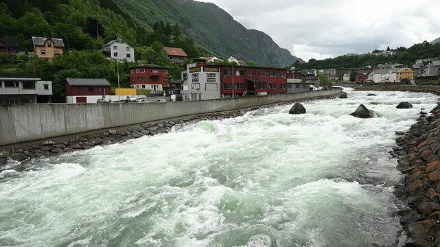 River Opo rushes through Odda town valley with strong current and whitewater in slow motion Norway