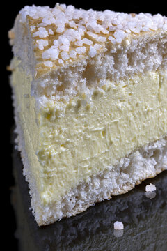 Closeup shot of a slice of tarte tropezienne on black background with a reflection