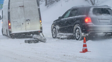 A breakdown on a winter road. Two cars on the side of the road. The car has a broken tire. Traffic accident on a snowy road on the highway. High quality photo