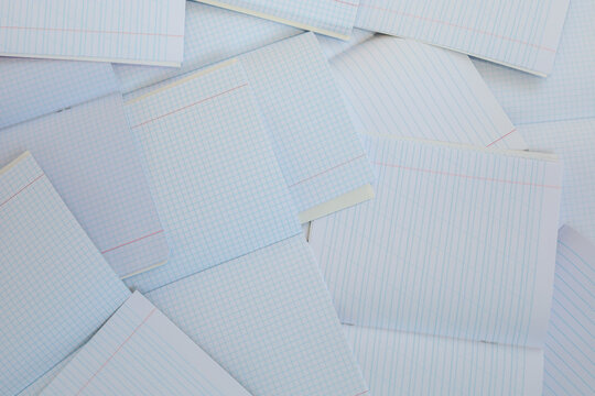 A messy pile of open student notebooks with blank ruled and squared pages. Light background of paper texture with red margins is ideal for themes related to the start of studies, exams, or planning da