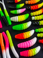 Bright fishing bait displayed on a dark surface with various shapes and colors in a neat arrangement for easy selection