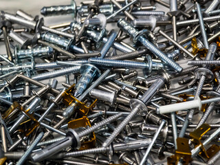 Mixed collection of metal screws and fasteners scattered on a flat surface for assembly and construction tasks