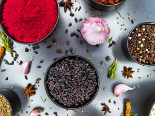 Colorful spices and herbs arranged in bowls on a kitchen counter with garlic and seeds nearby during daytime