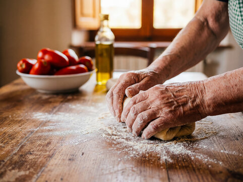 Elderly italian woman making homemade pasta flour on wooden table traditional cooking kitchen lifestyle grandmother family culture background copy space mediterranean food