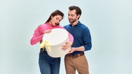 Couple opening large gift box together with joyful emotion. Concept of Saint Valentines Day, holiday advertising, seasonal promotion, retail marketing visuals, branding for gift sales.