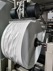 Large roll of cellophane on machine in packaging factory during day time