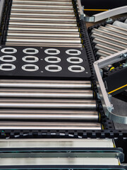 Conveyor belt system used in manufacturing process with metallic rollers in a production facility