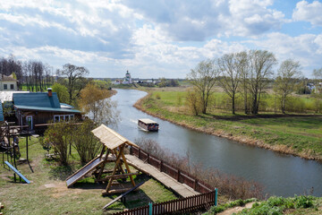 Fototapeta premium River with boat and church in peaceful spring village landscape