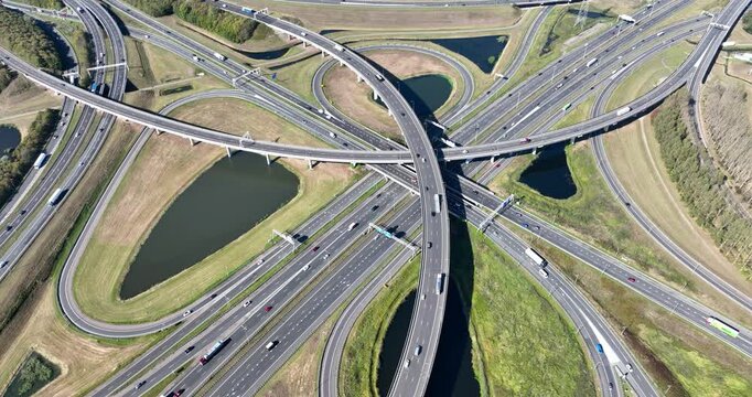Aerial view of a multilevel highway interchange with busy car traffic. Modern urban infrastructure, road junction, and city transportation system from above. Drone shot of cars.