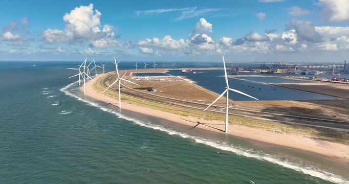 Aerial view of wind turbines on a sandy beach along the sea coast. Drone shot of a coastal wind farm generating renewable energy under a clear sky. Sustainable power infrastructure.