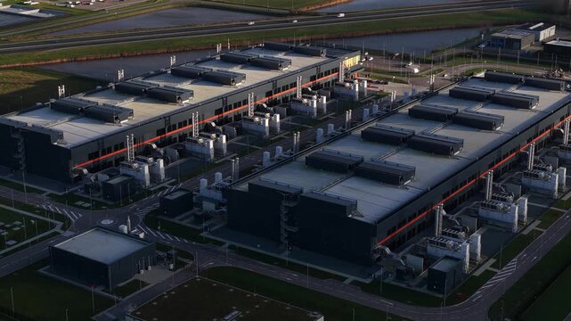 Aerial view of large Agriport buildings with dark roofs, surrounded by green spaces and roads, creating an industrial landscape, Middenmeer, Noord Holland, Netherlands.