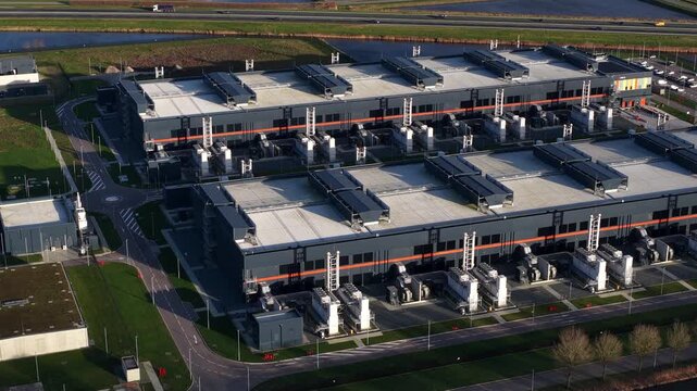 Aerial view of the industrial Agriport buildings with dark gray walls and light gray roofs, surrounded by green lawns and parking lots, Middenmeer, Noord Holland, Netherlands.
