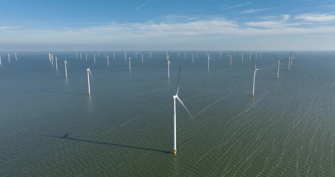 Aerial view of an offshore wind farm in the sea under a clear sky. Drone shot of wind turbines generating renewable energy in the ocean. Concept of clean sustainable power, green technology.