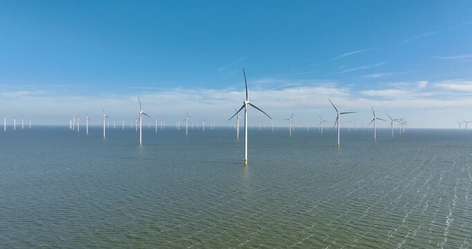 Aerial view of an offshore wind farm in the sea under a clear sky. Drone shot of wind turbines generating renewable energy in the ocean. Concept of clean sustainable power, green technology.