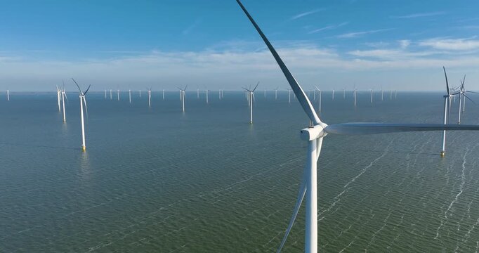 Aerial view of an offshore wind farm in the sea under a clear sky. Drone shot of wind turbines generating renewable energy in the ocean. Concept of clean sustainable power, green technology.