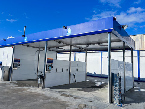 A self-service car wash bay equipped with high-pressure wands, foam brushes, payment terminals, offering drivers a convenient and efficient cleaning solution. Automotive industry, business promotions