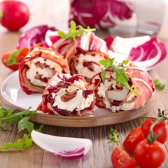 A plate of rolled food with herbs and vegetables on a wooden table