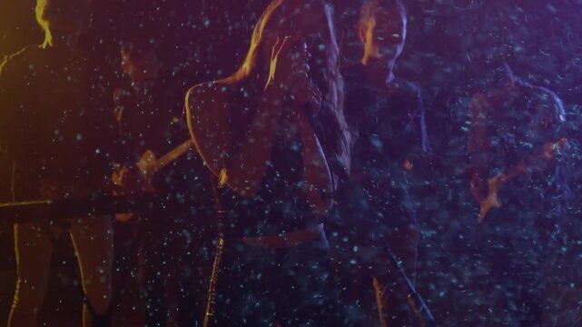 spray initiating rain as singer stepping forward raising mic stand singing music alongside band
