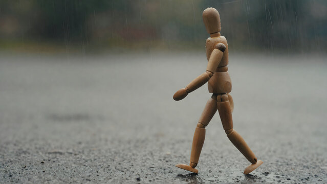 Solitary Wooden Mannequin Walking Through a Downpour on Wet Ground, Symbolizing Resilience