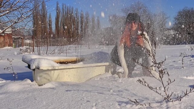 A young girl is outdoors emotionally throwing snow up, creating a dynamic winter shot with sunlight, movement and a sense of freedom.