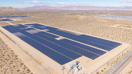 AERIAL: Barren landscape surrounds a large farm of solar panels in California. © helivideo