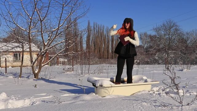 Young woman in old bathtub in the middle of a snowy field enjoying the winter sun, humorous atmosphere, freedom, relaxation and creative winter mood.