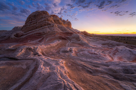 View of layered sandstone formations painted with hues of pink and cream under a sky ablaze with the colors of sunset, Marble Canyon, Arizona, United States.