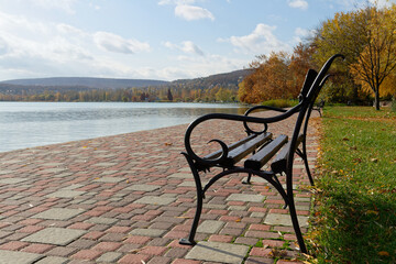 A scenic bench by a lake offers a perfect spot for relaxation amidst autumn foliage.