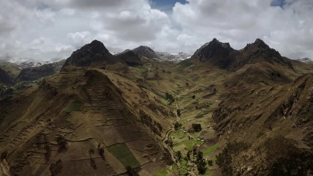 Panoramical shoot from The Andes. The mountains in the back are covered in snow and the sky is cloudy. The mountains are very tall and the snow is covering them. Cotopaxi, Ecuador.