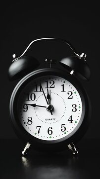 Clock face timelapse on black background. Time ticking on old fashioned alarm clock with bells. Time moving fast. Time concept. Table clock show running time. Vertical. Close-up in 4K, UHD
