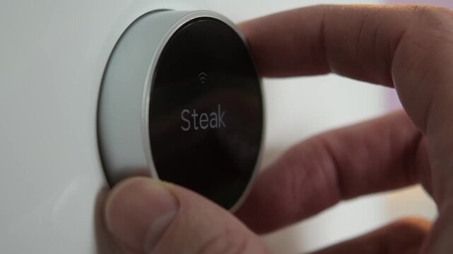 Hand rotates smart air fryer dial to browse touchscreen cooking presets, switching from manual control to automated menu.