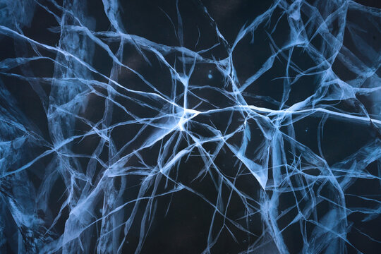 View of intricate, icy fractals spiderweb across the dark expanse, like frozen lightning, capturing the stark beauty of a polar landscape, Coldfoot, Alaska, United States.
