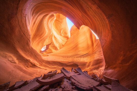View of swirling sandstone walls embrace the sky, a dance of light and shadow in nature's cathedral, rocks scattered on the ground, Escalante, Utah, United States.