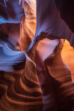 View of swirling sandstone walls carved by time and light, where cool blues meet warm oranges in a dance of shadows and textures, Escalante, Utah, United States.