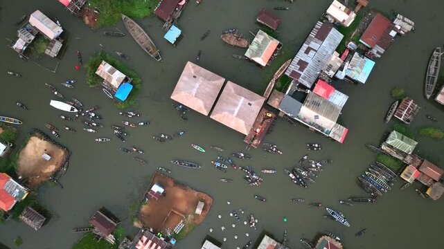 Aerial view of houses constructed on water, with boats navigating between them creating a vibrant contrast against the still water, Ganvie, Atlantique Department, Benin.