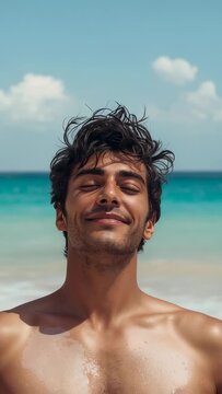 Vertical video: Breathing shirtless man resting, tilting head, wind lifting chest droplets at shore