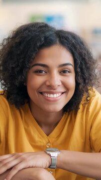 Vertical video: Leaning woman laughing at camera zooming in study, wearing mustard and silver watch