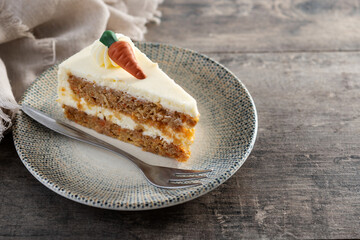 Carrot cake slice with cream cheese frosting on wooden table. Copy space