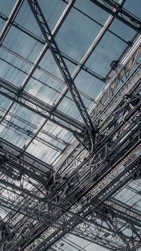 Vertical video: Tilting camera revealing steel glass roof junction at transit hall, showing trusses