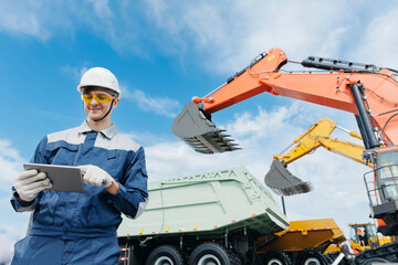 Caucasian male engineer in hard hat supervising excavator at mining site