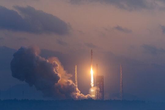 Rocket launch at dawn with billowing smoke against clouded sky and big flames, moment of liftoff