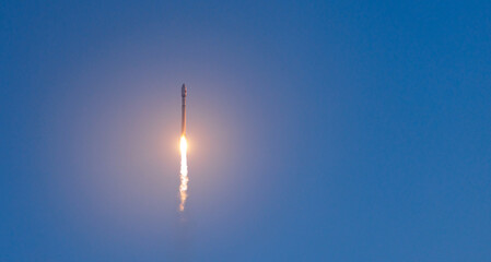 Fototapeta premium Rocket with satellites launch against clear blue sky at daytime, banner of concept aerospace program